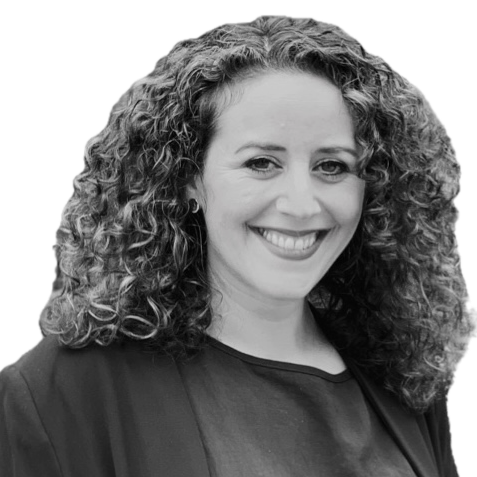Smiling woman with curly hair wearing a dark top against a plain background.